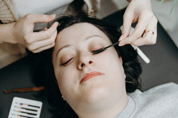 Portrait of a girl cosmetologist combing a woman's eyelashes.