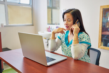 latin woman health professional sitting in her office talking on the cell phone