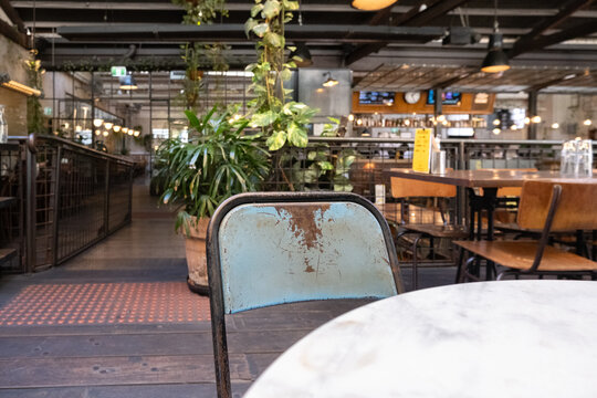 a chair with a weathered retro style backrest, with a blurry interior of a café or restaurant with an industrial and rustic design. The ambiance of a trendy, urban eatery with aesthetics and comfort