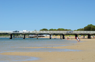 Summer scenery of a shallow beach with many tourists enjoying the sun and water, the Barwon Heads...