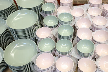 A large pile of white and pink bowls and plates
