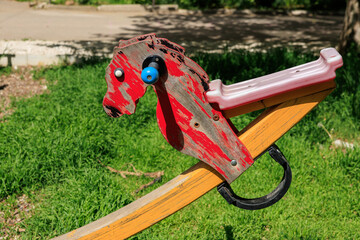 A wooden horse with a blue and black head is sitting on a wooden plank