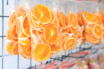 Three bags of orange slices are hanging on a metal rack, dried fruits for tea