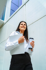 One young successful business woman  going to work at business office modern building while holding coffee and papers