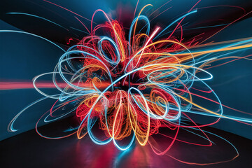 Vibrant light painting with swirling, colorful light trails in dark room, creating abstract and dynamic visual effect.