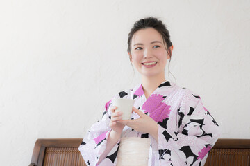 Woman in yukata drinking a beverage, e.g. tea or matcha
