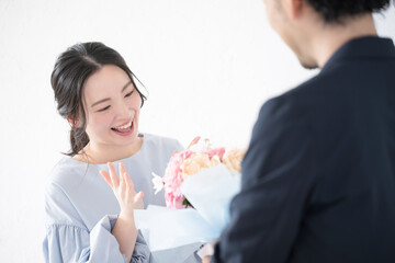 花束のプレゼントを受け取る若い女性と贈る男性の顔無し