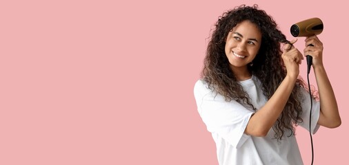 Happy African-American woman with hair dryer on pink background with space for text