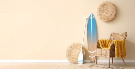 Armchair, surfboard and paddle near beige wall in room. Banner for design