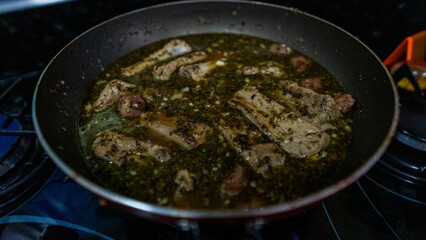 Ribs frying in the pan with chopped garlic and olive oil