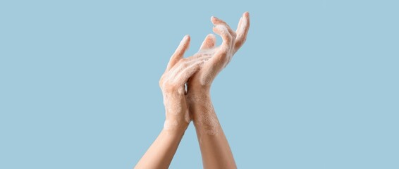 Hands in soap foam on light blue background