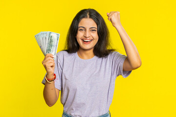 Rich pleased happy Indian young woman waving money dollar cash banknotes bills like a fan, success...