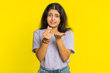 Give me money, please. Indian woman rubbing fingers show cash gesture, demands to pay back the debt, take loan, do shopping, begging, investment, reward. Arabian girl isolated on yellow background