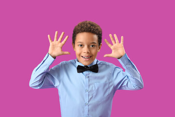 Little African-American boy waving hands on purple background