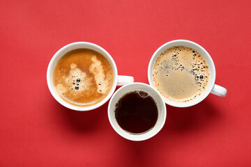 Cups of hot coffee on red background