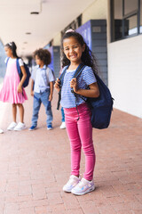 A young biracial girl with curly brown hair smiles outside school