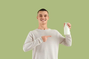 Teenage boy pointing at bottle of milk on green background