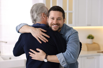 Happy son and his dad hugging at home