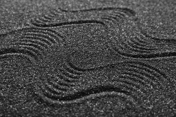 Texture of black sand with lines, closeup. Zen concept
