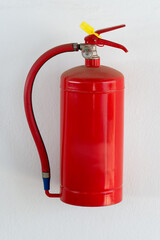 red powder extinguisher hanged on a white wall