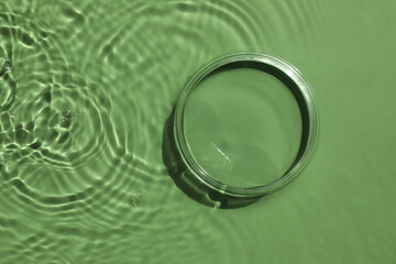Stylish presentation for product. Glass podium in water on pale green background, top view