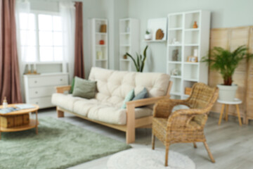 Blurred view of cozy living room with sofa, table and drawers