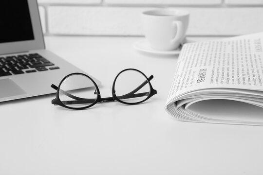 Glasses with newspaper on white table
