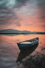 Naklejka premium boats waiting in the reflective water clouds in the sky sunset colors