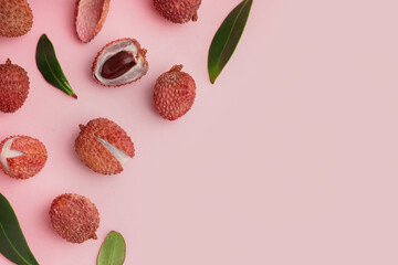 Tasty litchi fruit and leaves on pink background