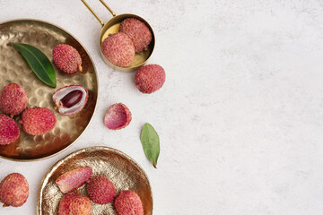Plates with tasty litchi fruit on light background