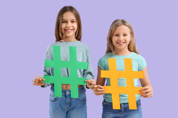 Cute teenage girls with hashtags on lilac background