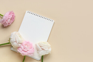 Beautiful ranunculus flowers with open notebook on beige background
