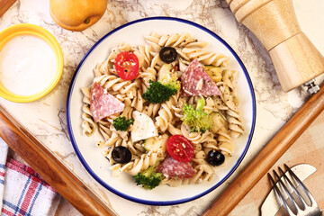 Bowl of tasty pasta salad with omatoes, ham, black olives, broccoli and cheese 