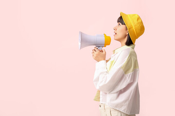 Young woman with megaphone  on pink background