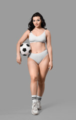 Beautiful young body positive woman with soccer ball in stylish underwear on grey background