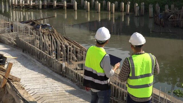 Engineers Civil and supervisors are discussing construction of a bridge across the river,Architects came to control the construction design.