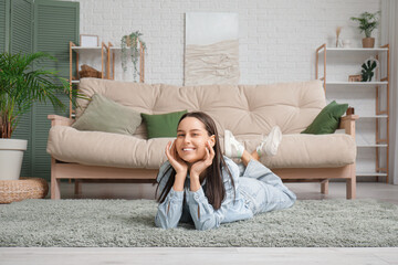 Obraz premium Young woman lying on floor near sofa in living room