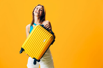 The joyful journey ahead a smiling woman holding a yellow suitcase against an orange background