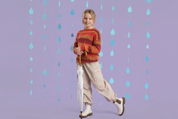 Adorable girl with umbrella and paper raindrops on lilac background