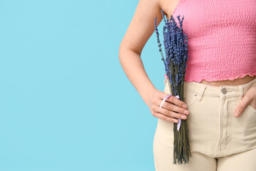 Beautiful young woman with bouquet of lavender flowers on blue background, closeup
