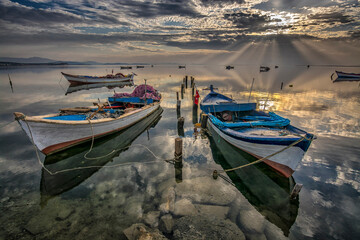 boats waiting in the reflective water clouds in the sky sunset colors