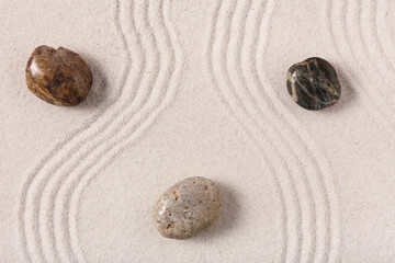 Stones on sand with lines in Japanese rock garden, flat lay. Zen concept