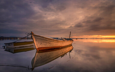boats waiting in the reflective water clouds in the sky sunset colors