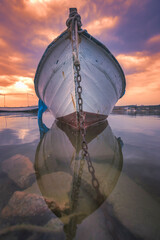 boats waiting in the reflective water clouds in the sky sunset colors