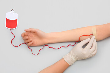 Female hands with paper blood pack for transfusion on grey background. Donation blood concept.