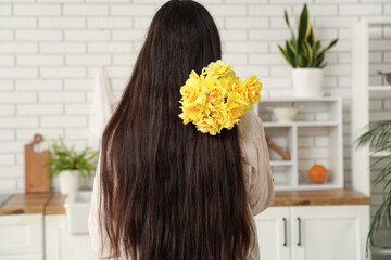 Beautiful young woman with narcissus bouquet at home, back view