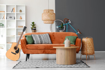 Interior of living room with brown sofa, coffee table, acoustic guitar and bicycle