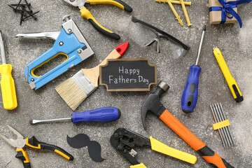 Tools, gift box and greeting card with text HAPPY FATHER'S DAY on grey grunge background