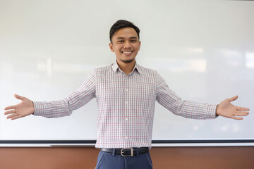 A smiling Malay male teacher welcoming student in classroom