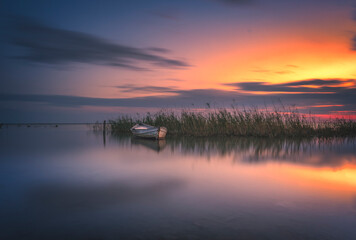 boats waiting in the reflective water clouds in the sky sunset colors